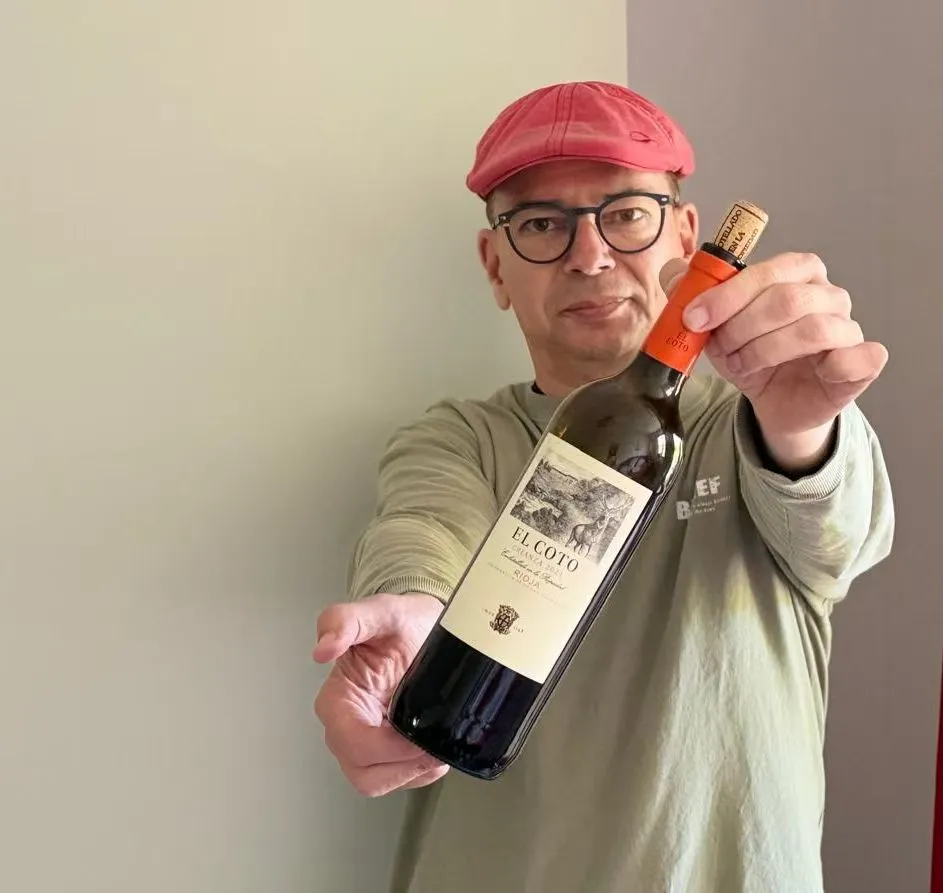 Ein Mann hält eine Flasche Wein in die Kamera